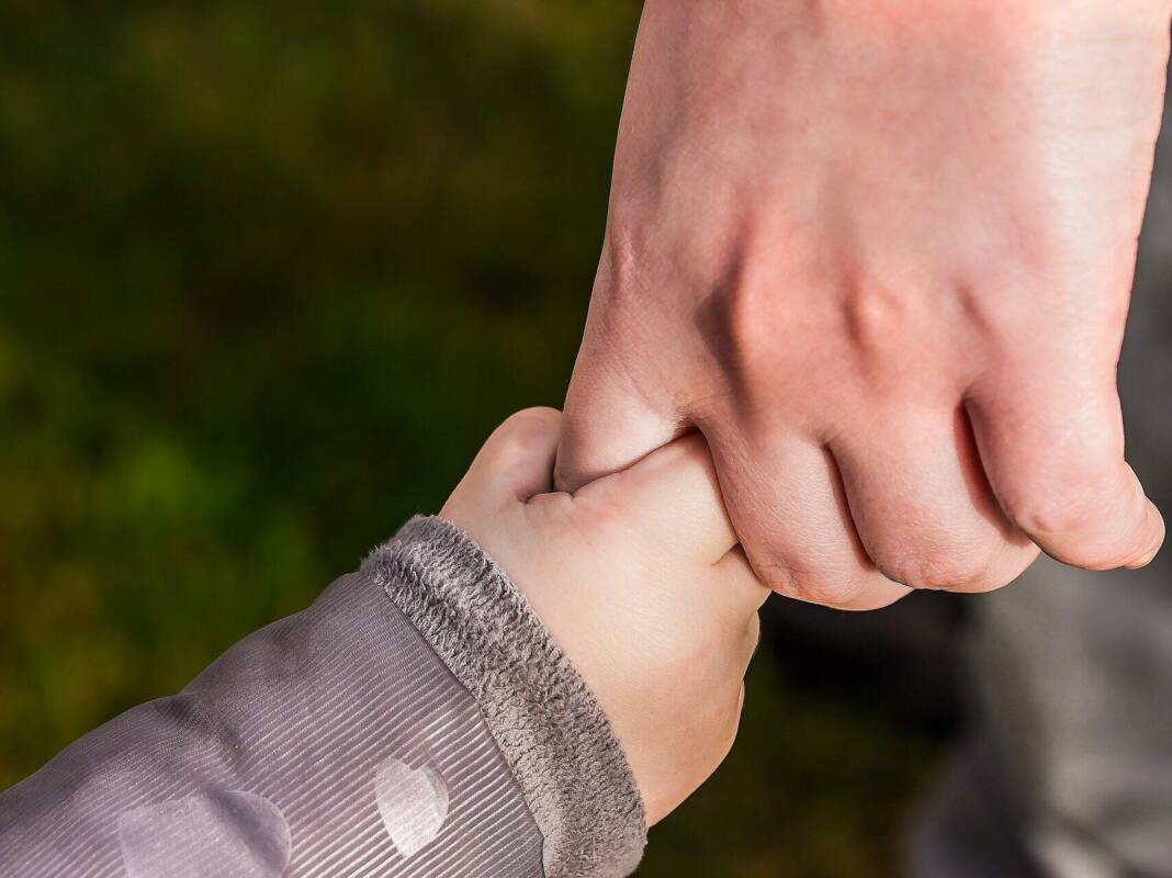 Hand eines Erwachsenen hält Kinderhand