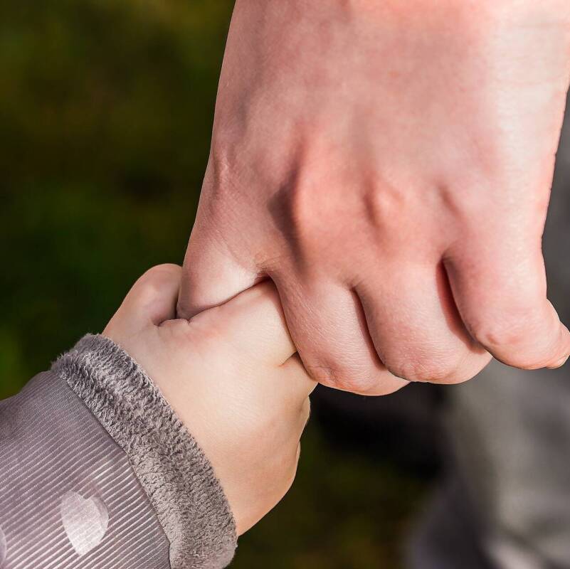 Hand eines Erwachsenen hält Kinderhand