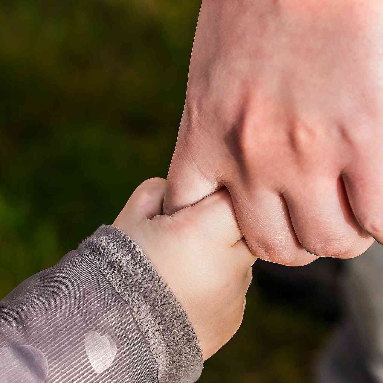 Hand eines Erwachsenen hält Kinderhand