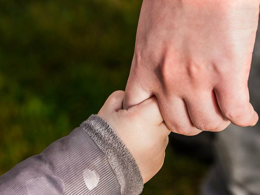 Hand eines Erwachsenen hält Kinderhand