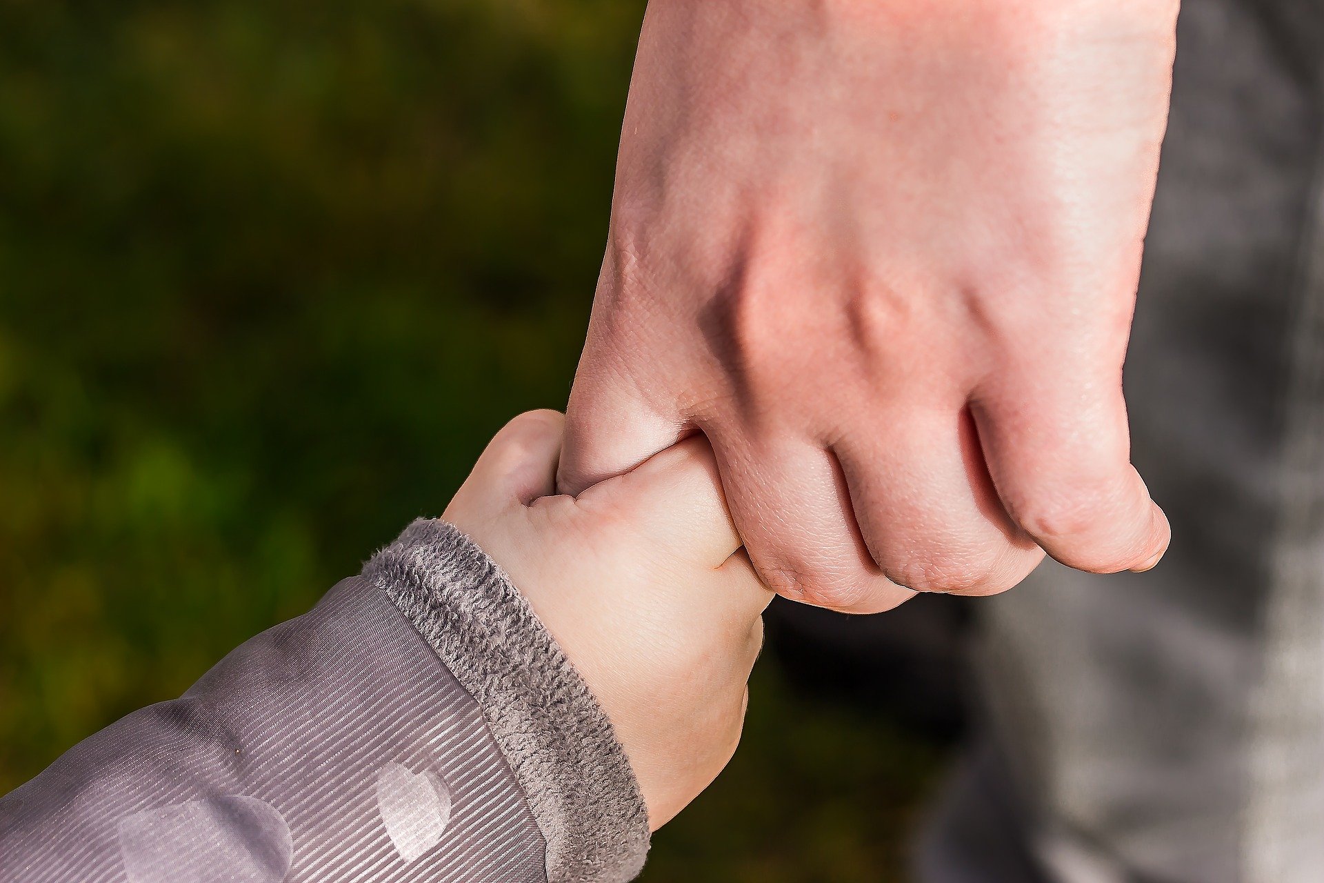 Hand eines Erwachsenen hält Kinderhand